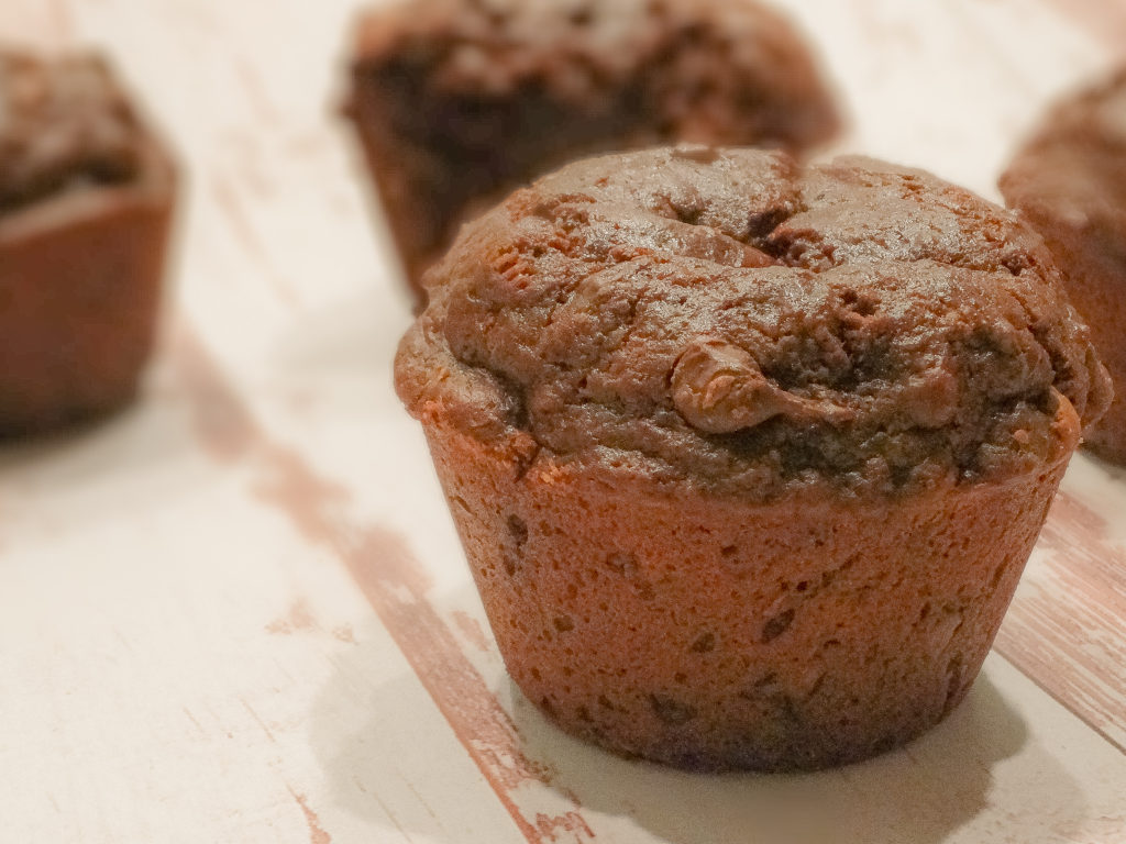 alt="double chocolate bakery style muffins with chocolate chips on a white marble cutting board"