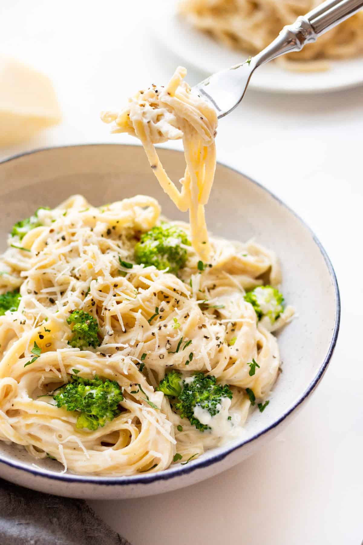 white pasta sauce tossed with broccoli in a serving bowl