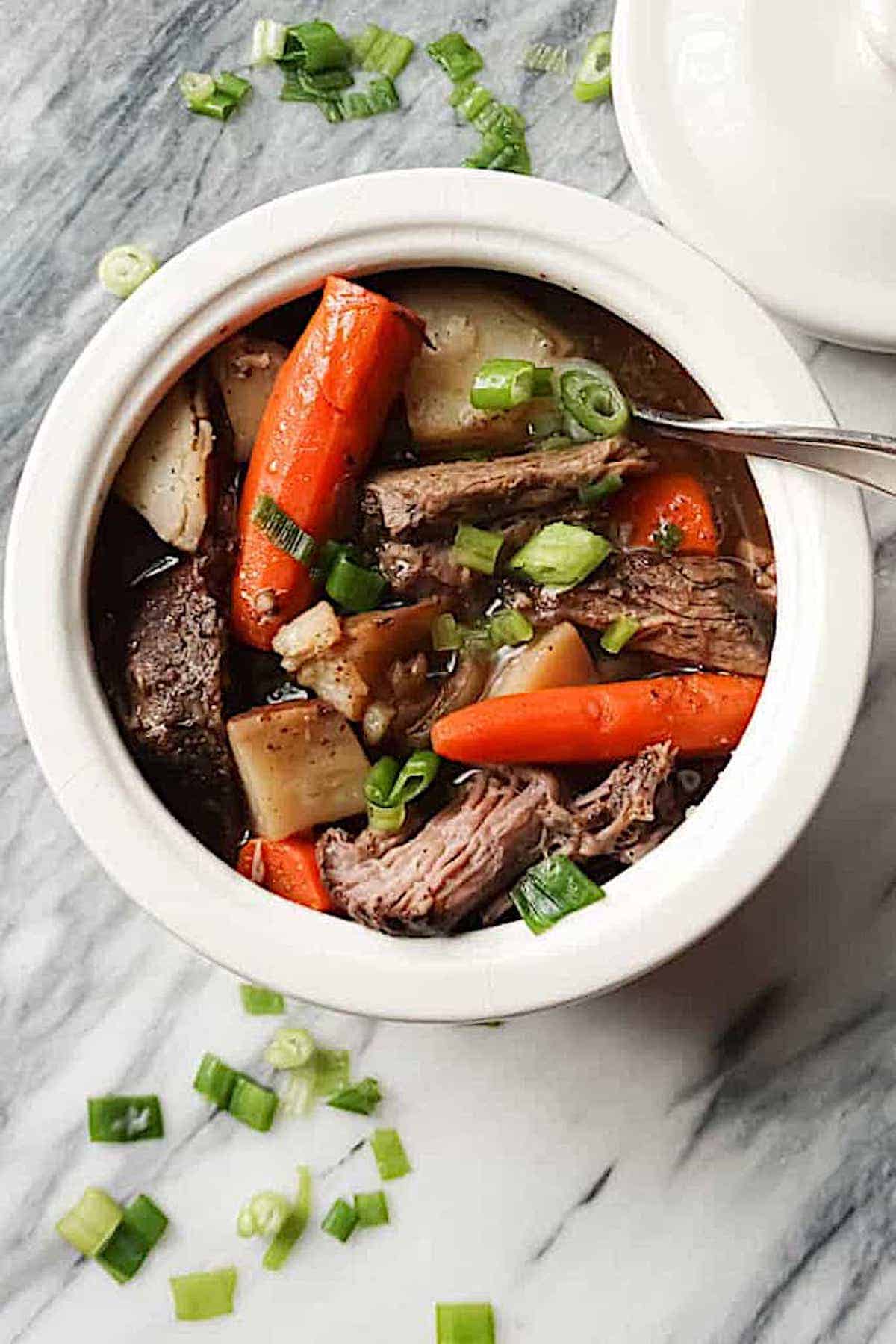 slow cooker beef roast in a white pot