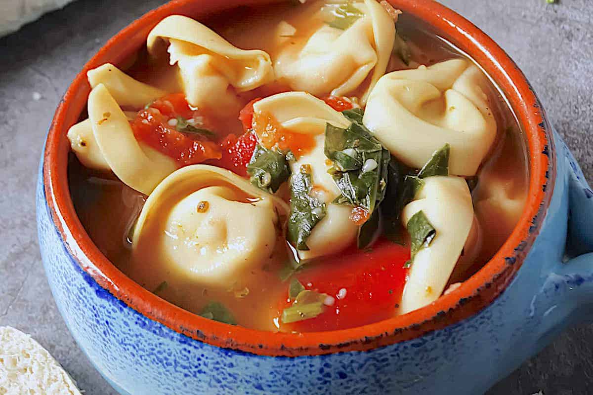 spinach tortellini soup in a blue cup