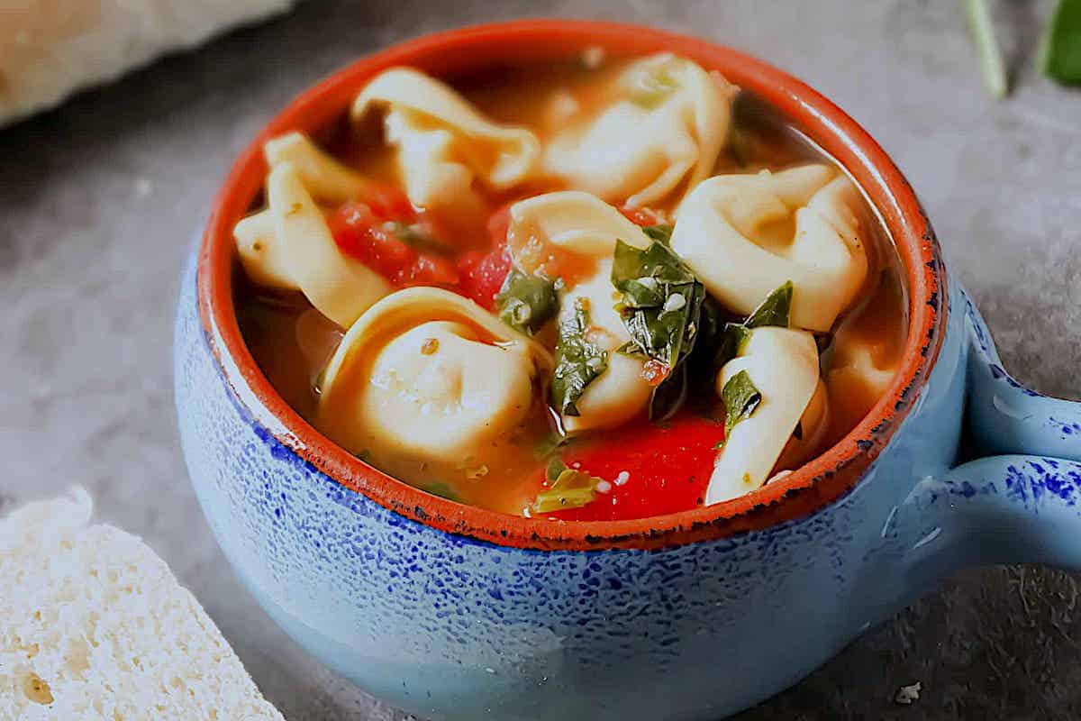 spinach tortellini soup in a blue cup