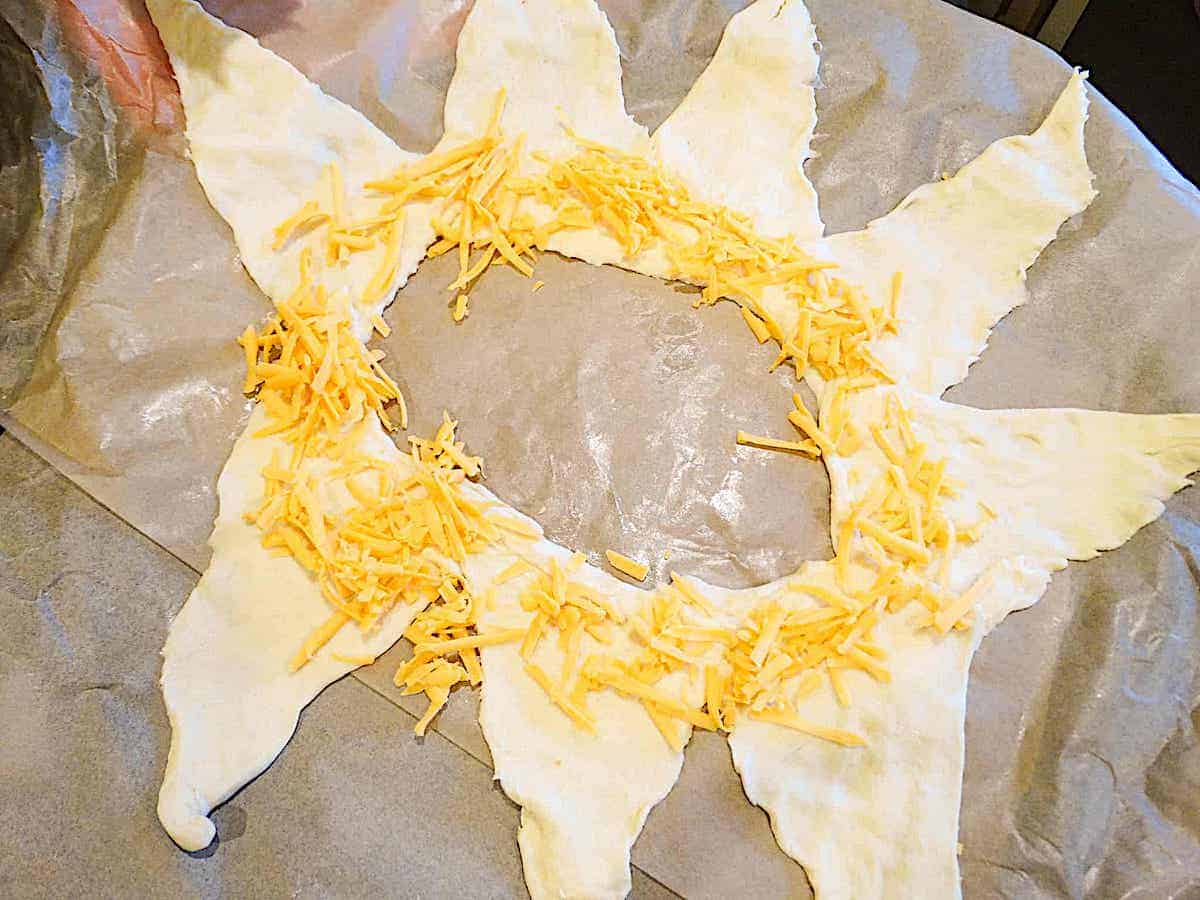 croissant dough rolled out and shaped into a star topped with cheddar cheese