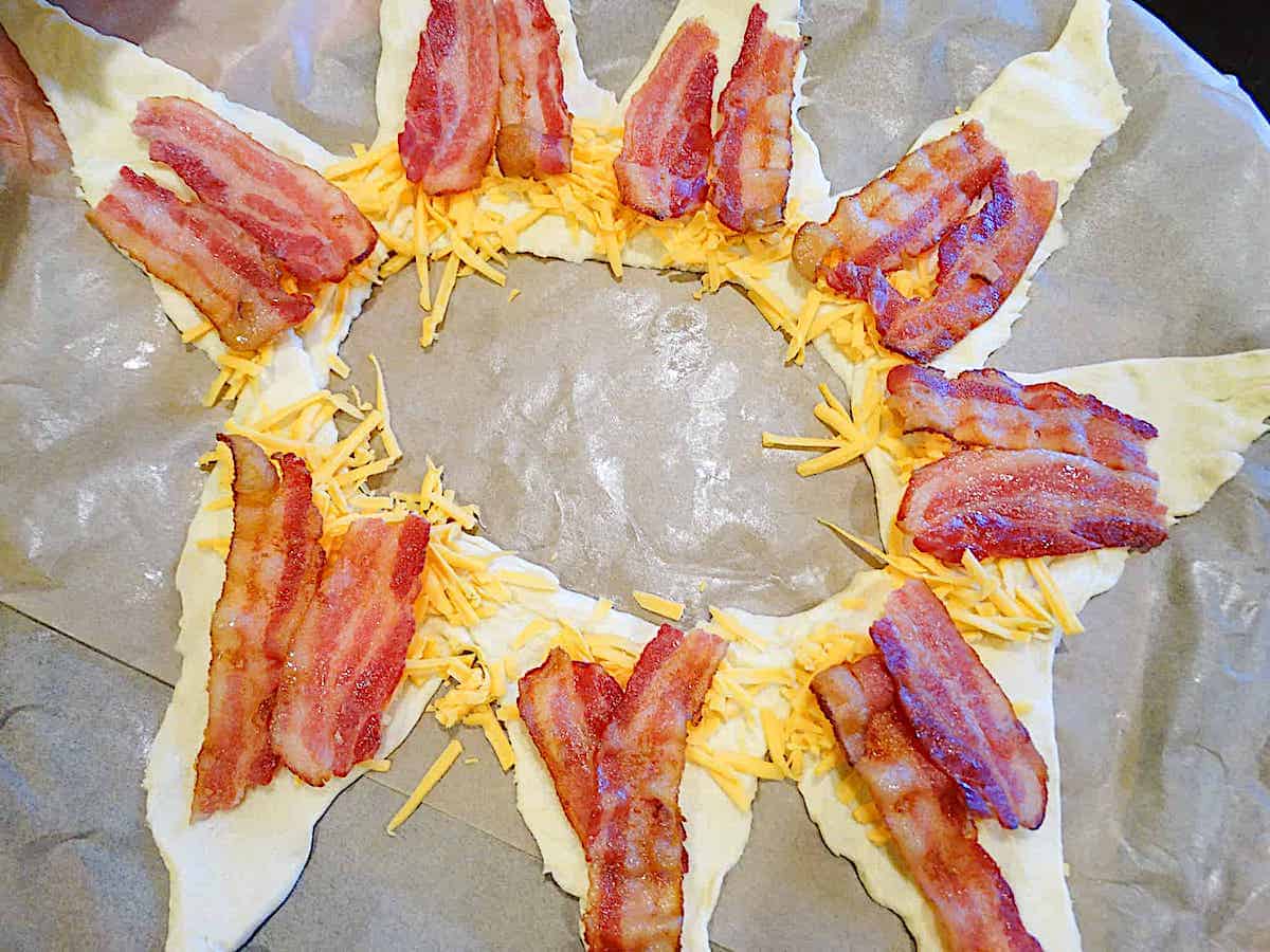 croissant dough rolled out and shaped into a star topped with cheese and bacon