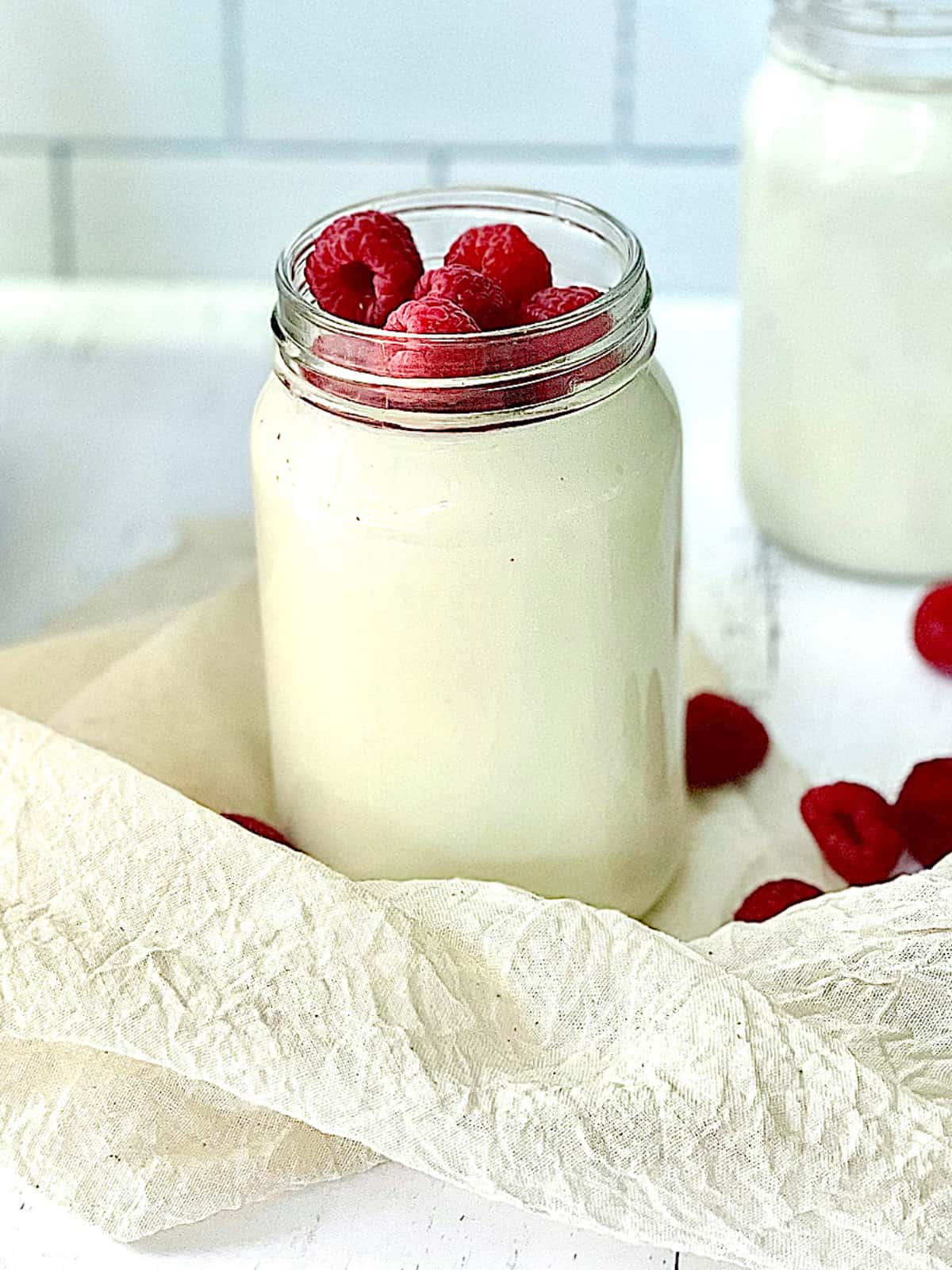 homemade Greek yogurt in a mason jar topped with raspberries