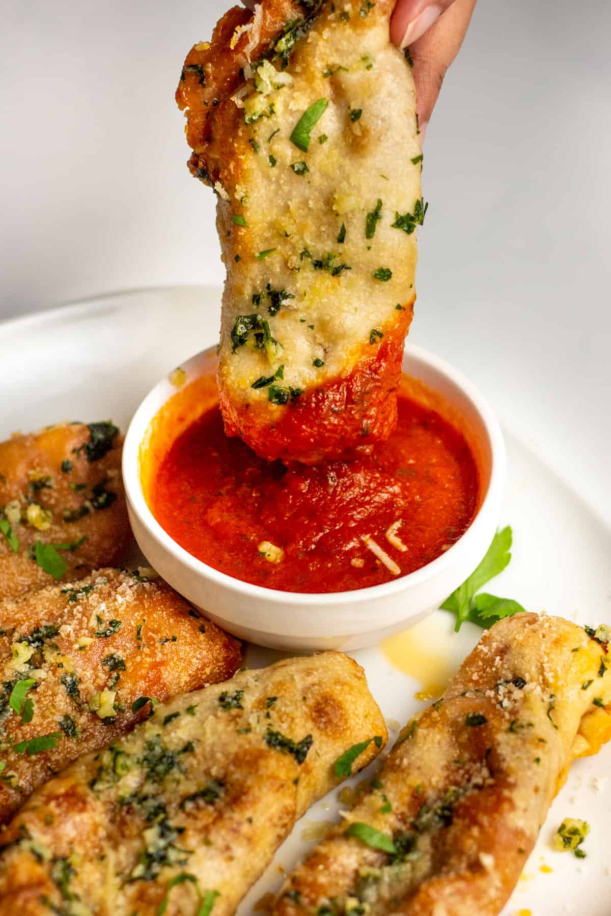 a pizza stick being dipped into marina sauce
