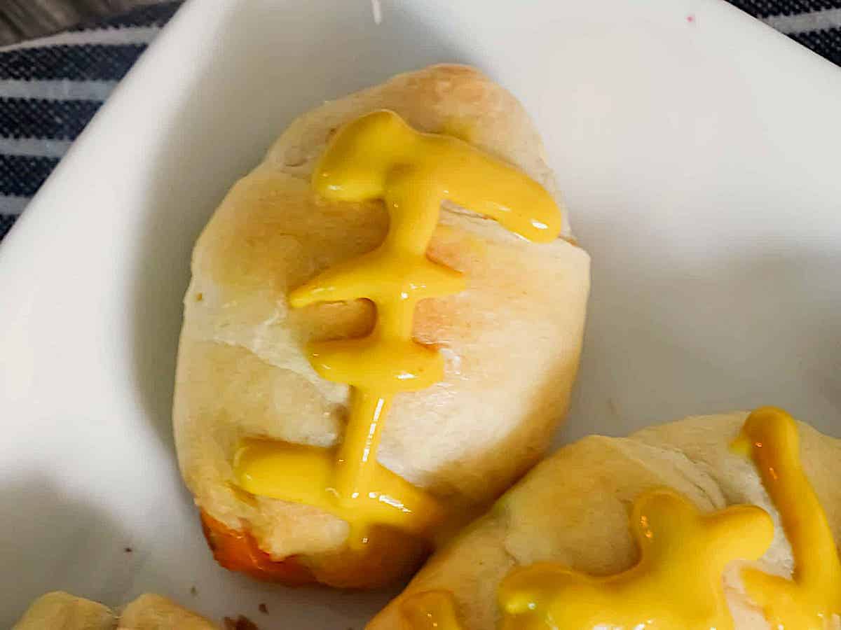 mustard lines on a football shaped mini crescent hot dog