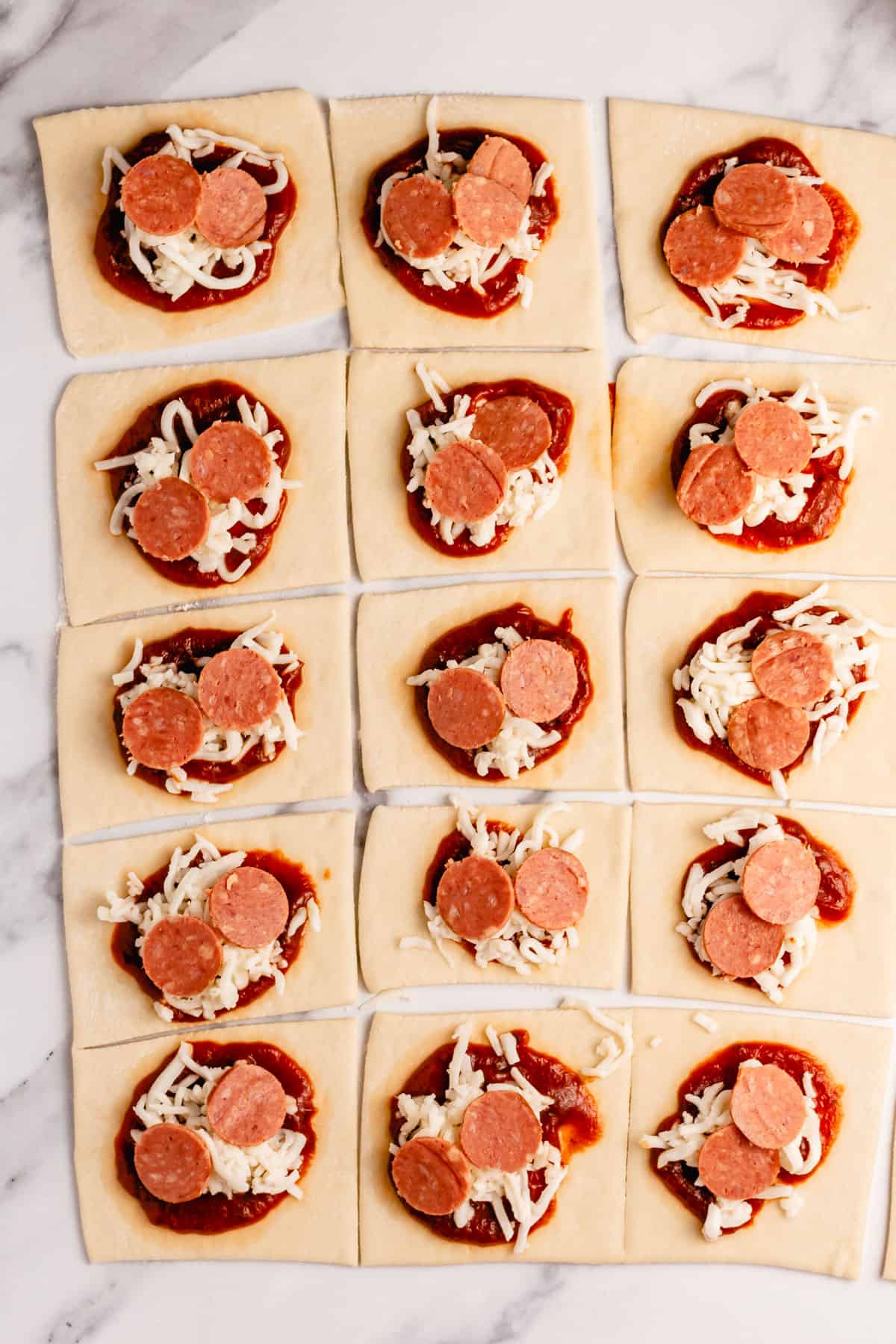 pizza dough squares topped with pizza sauce, mozzarella cheese, and pepperoni slices