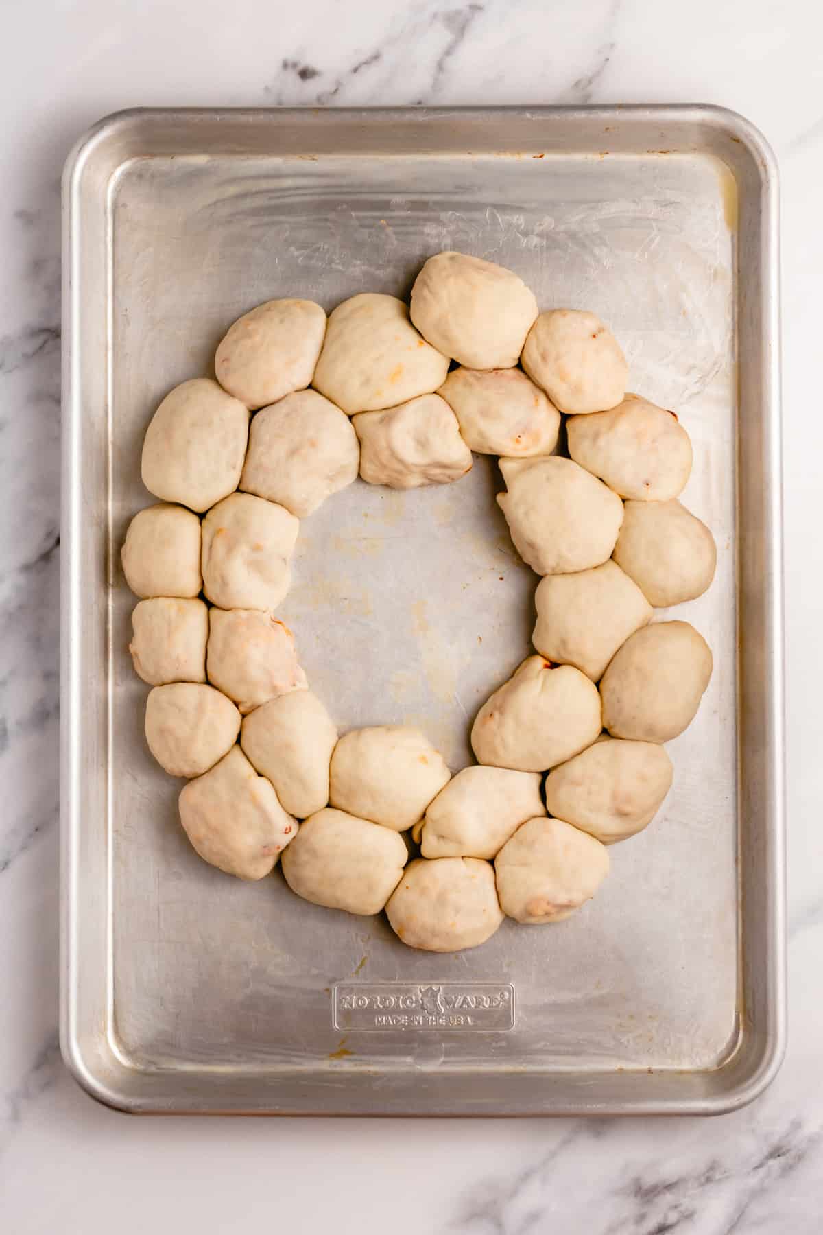 pizza dough balls shaped into a football on a baking sheet
