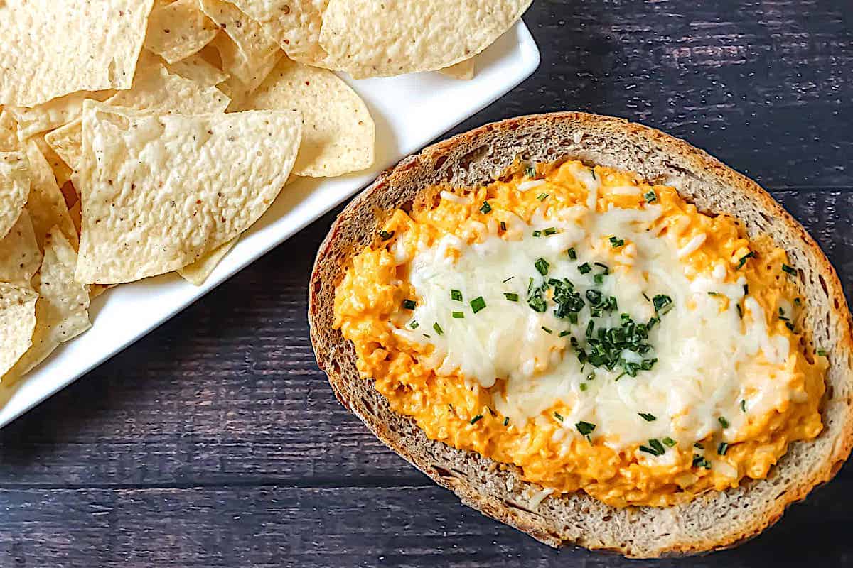 buffalo cauliflower dip in a bread bowl, topped with mozzarella and chives