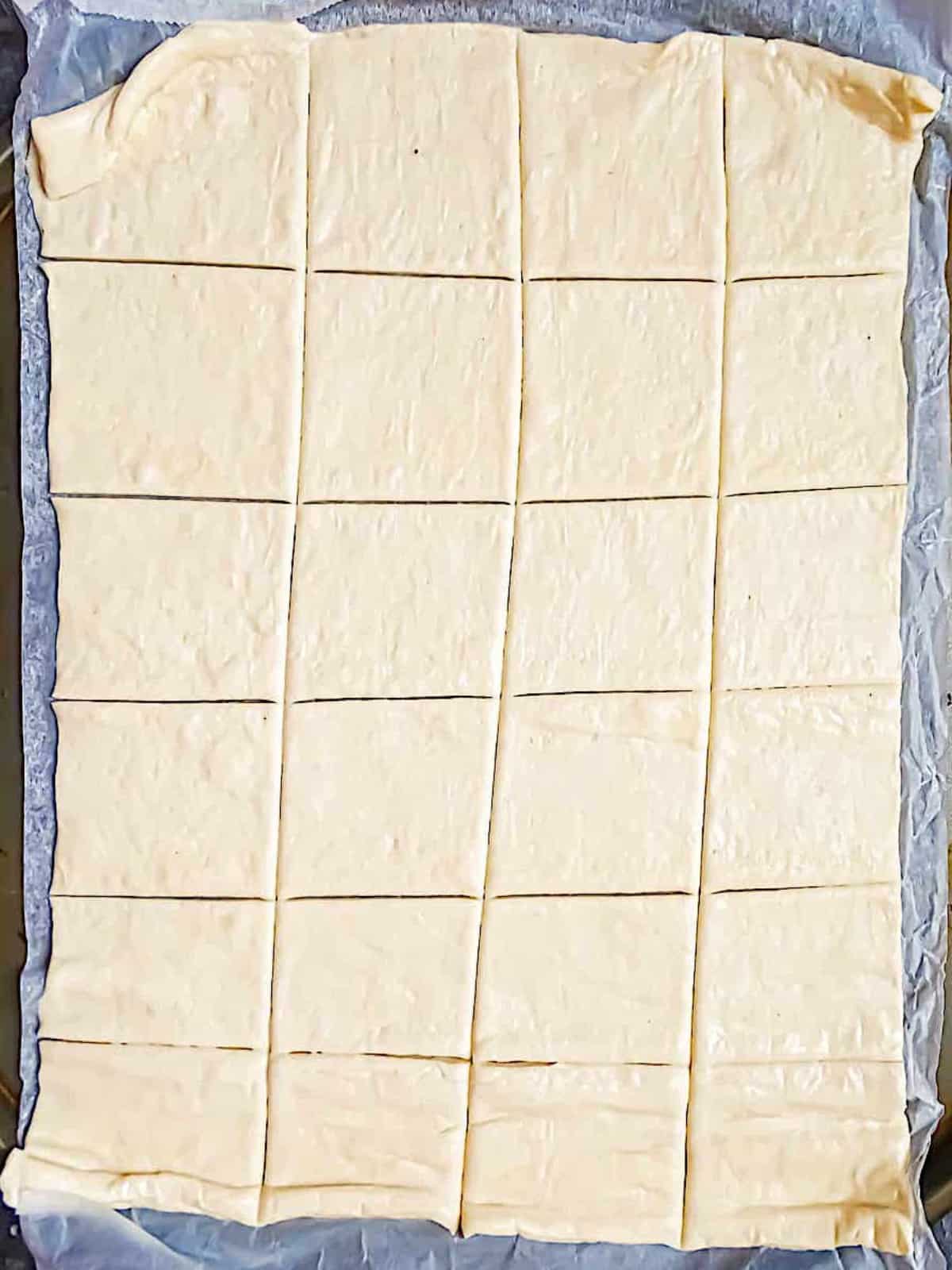 pizza dough spread onto a baking sheet and cut into pieces
