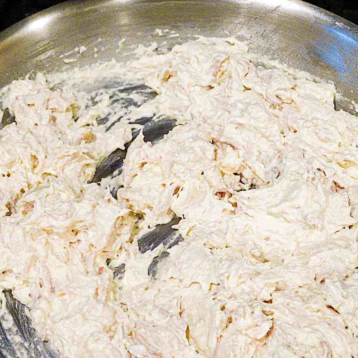 shredded chicken mixed with sour cream and cream cheese in a pan