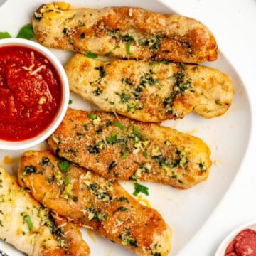 cheesy pepperoni pizza sticks on a white plate with dipping sauce