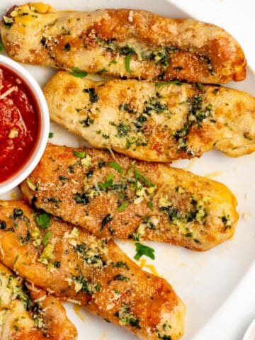 cheesy pepperoni pizza sticks on a white plate with dipping sauce