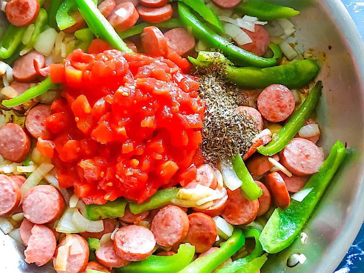 kielbasa, peppers, onions, garlic, and tomatoes in a frying pan