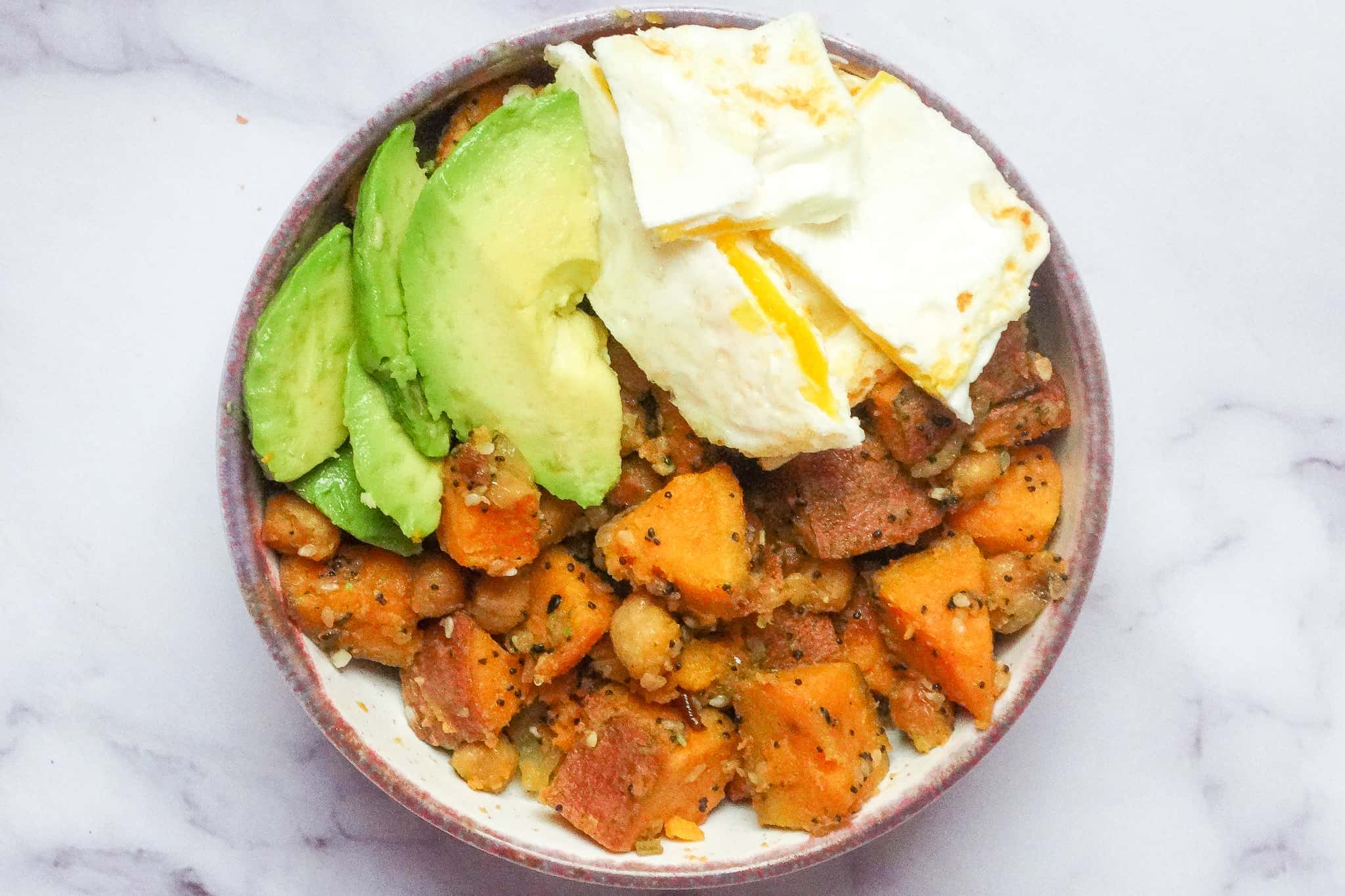 sweet potato chickpea hash with avocado and egg in a bowl