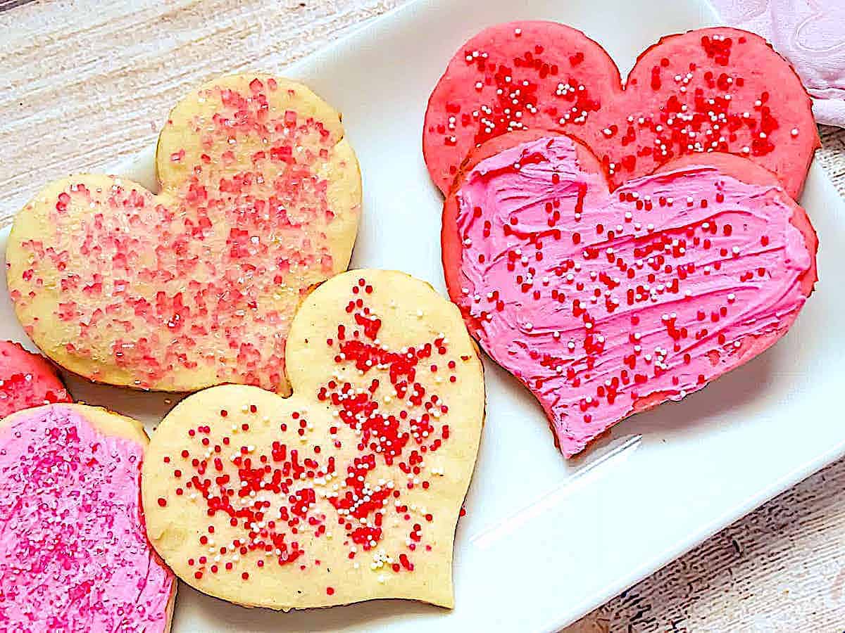 Valentine's heart shaped cookies topped with sprinkles and icing on a white plate