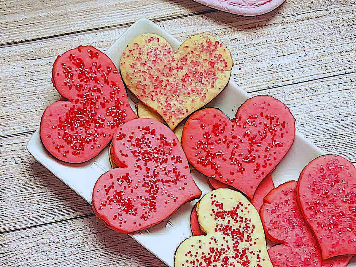 Valentine's Butter Cookies dyed pink and in the shape of hearts on a white plate