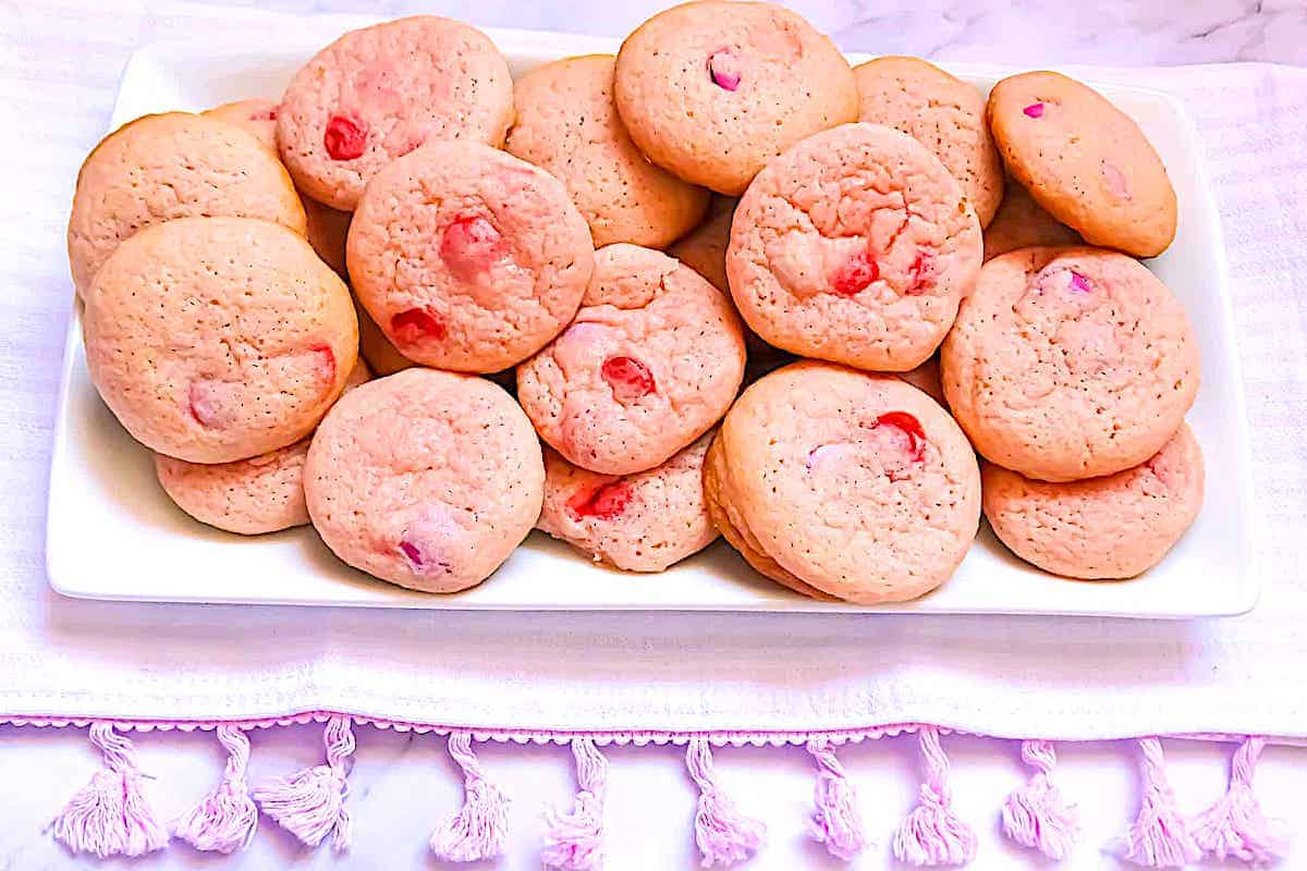 pink sugar cookies with m&ms on a white plate