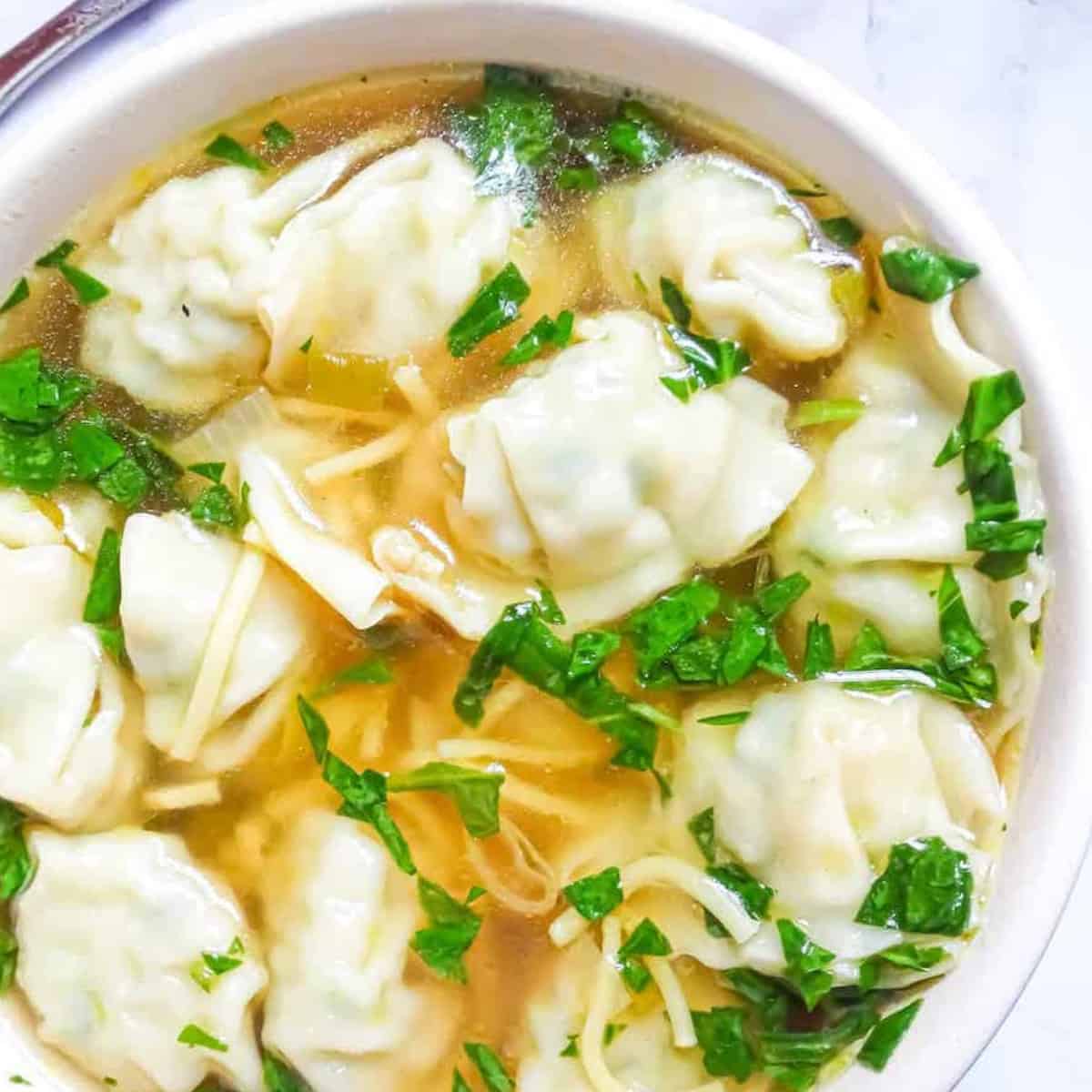 Instant Pot wonton soup with spinach in a white bowl