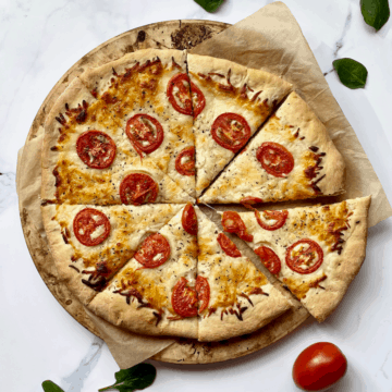 white pizza with tomato and basil on a white surface