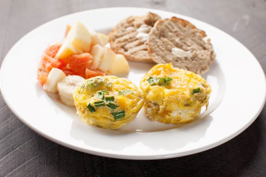 spinach egg muffins with sausage and fruit on a white plate 
