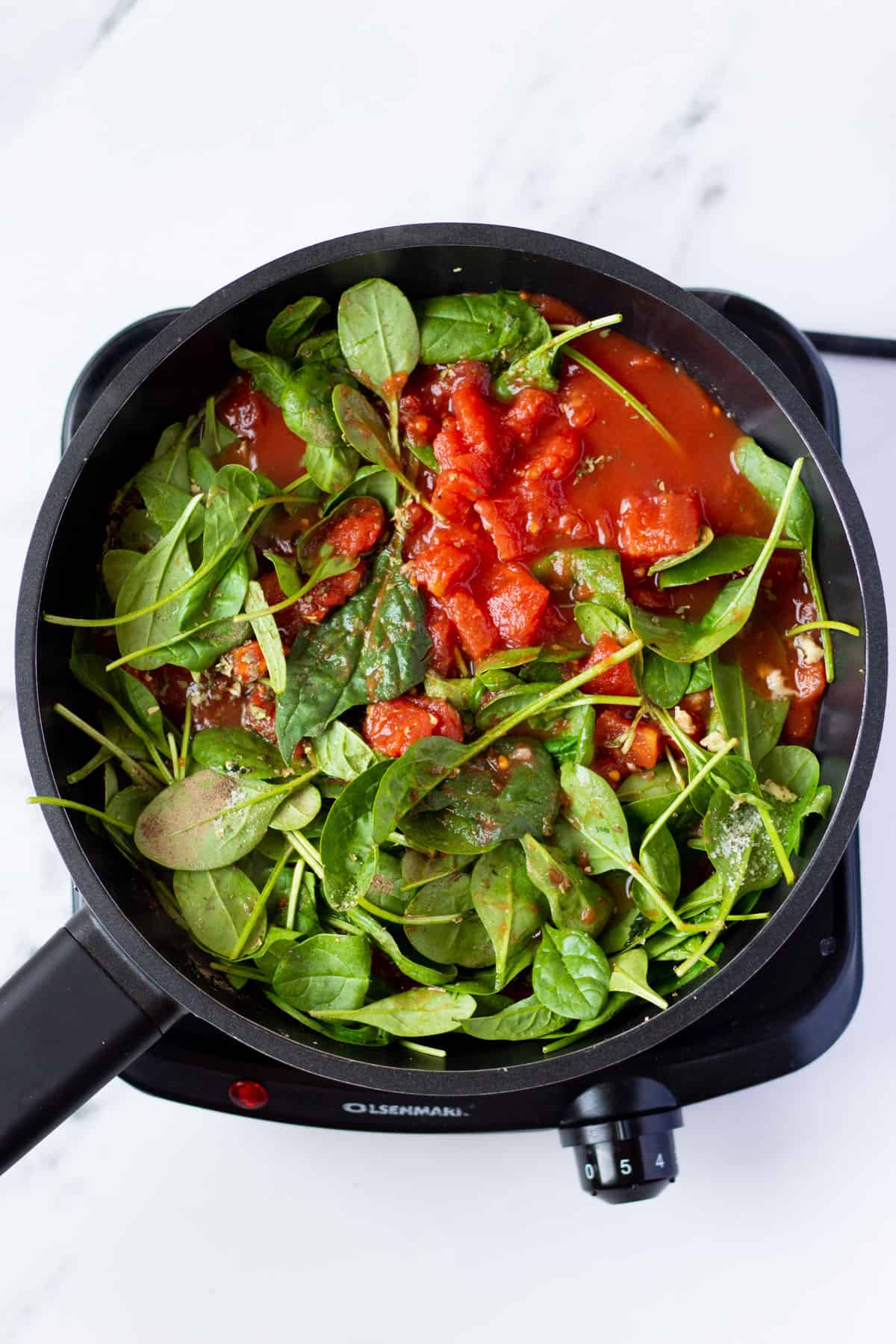 fresh basil leaves and diced tomatoes in a skillet