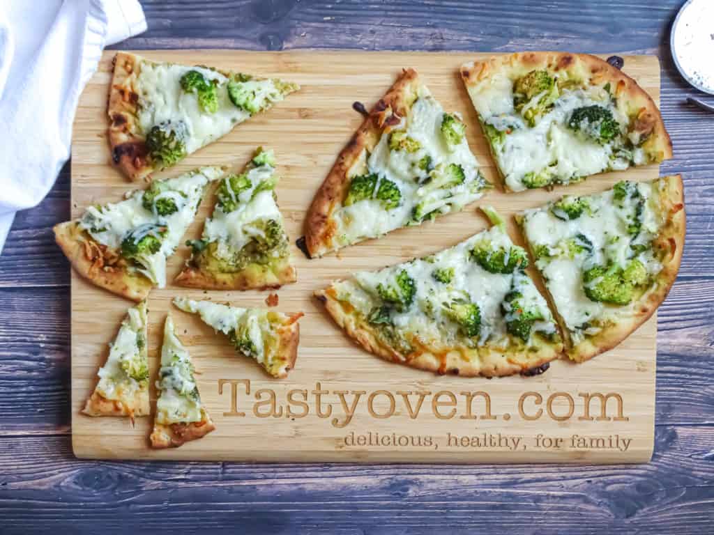 green pizza with broccoli cut into slices on a cutting board