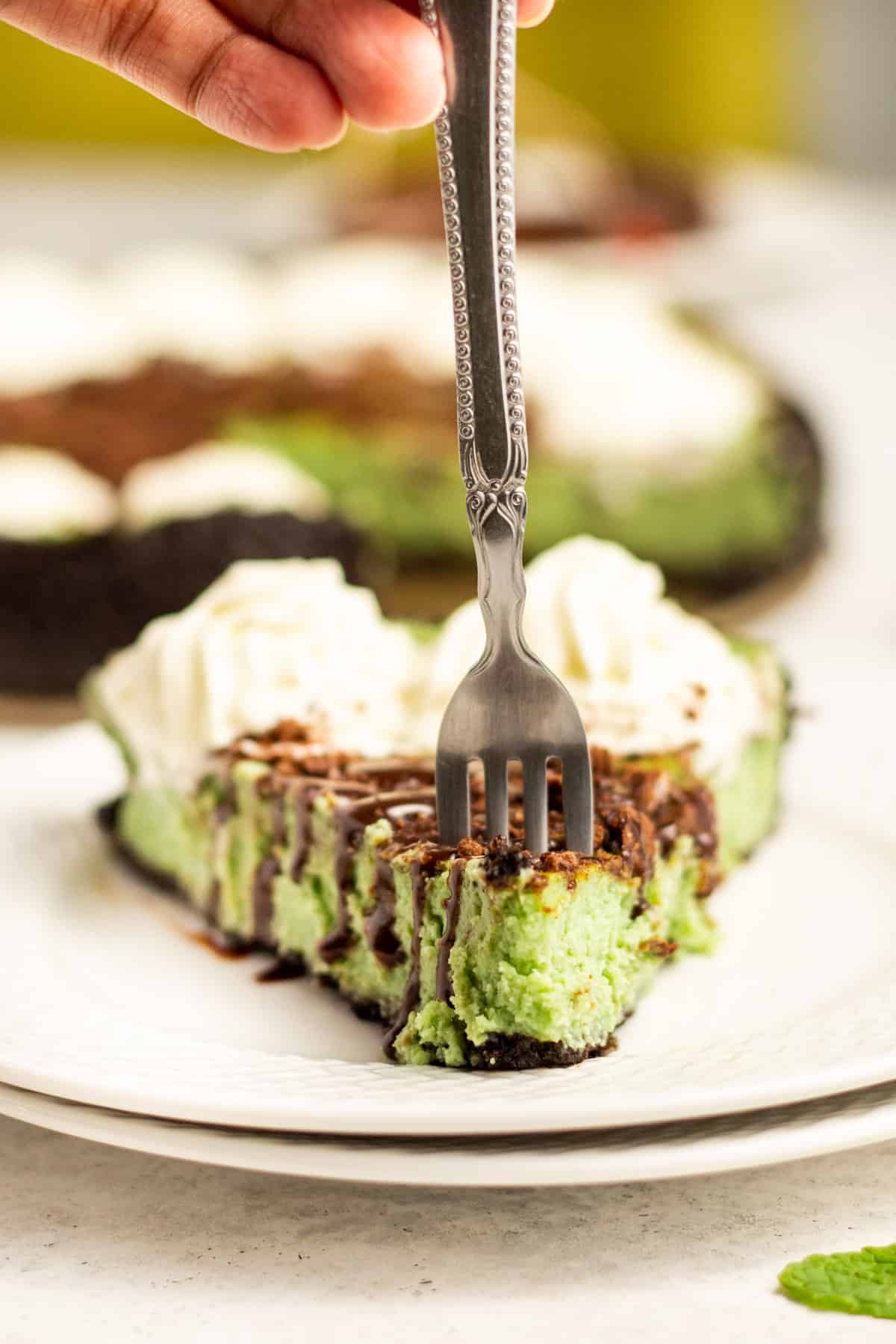 a fork stuck in a piece of mint chocolate cheesecake
