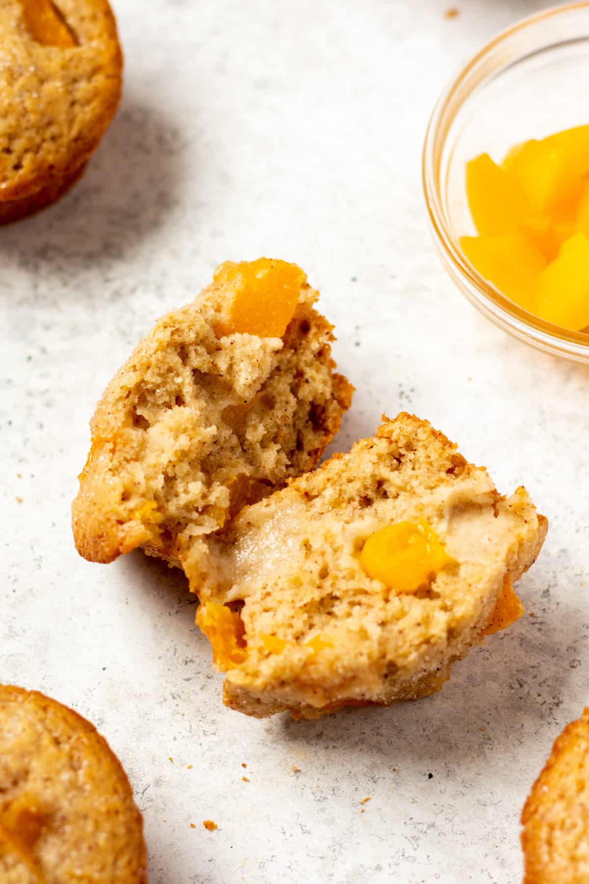 sliced open peach muffin on a white background