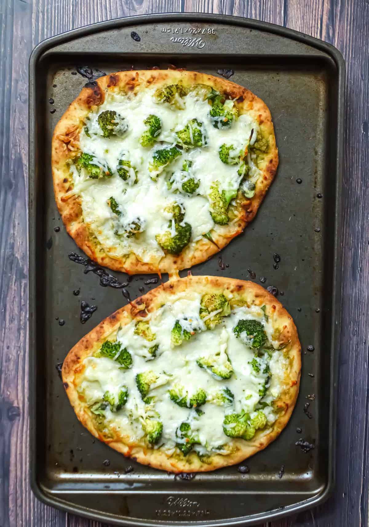 cooked green pizza on a baking sheet