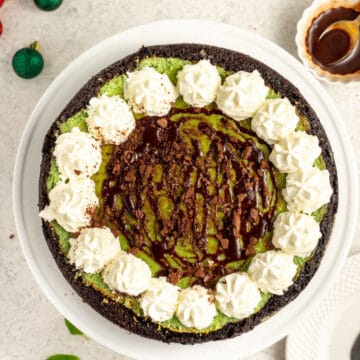 mint chocolate cheesecake topped with whipped cream, chocolate and sauce