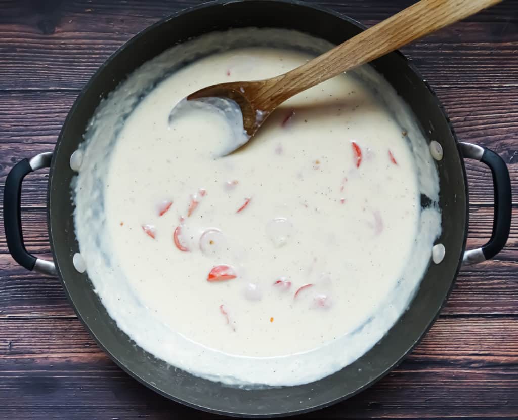 creamy white sauce for pasta and tomatoes in a wok