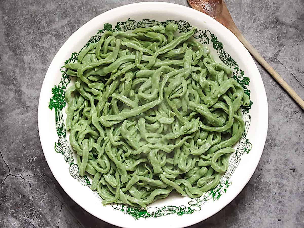 fresh cooked spinach pasta dough in a white bowl