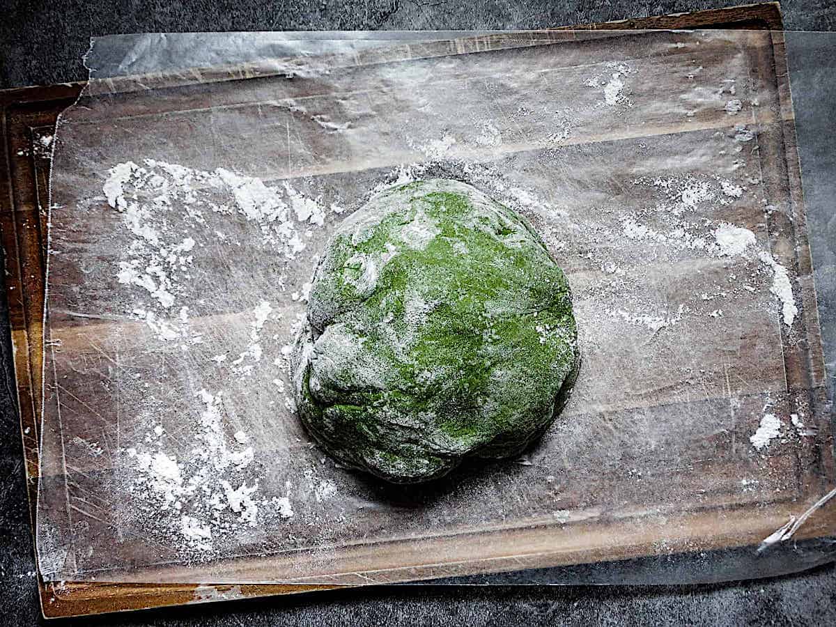 spinach pasta dough ball on a cutting board