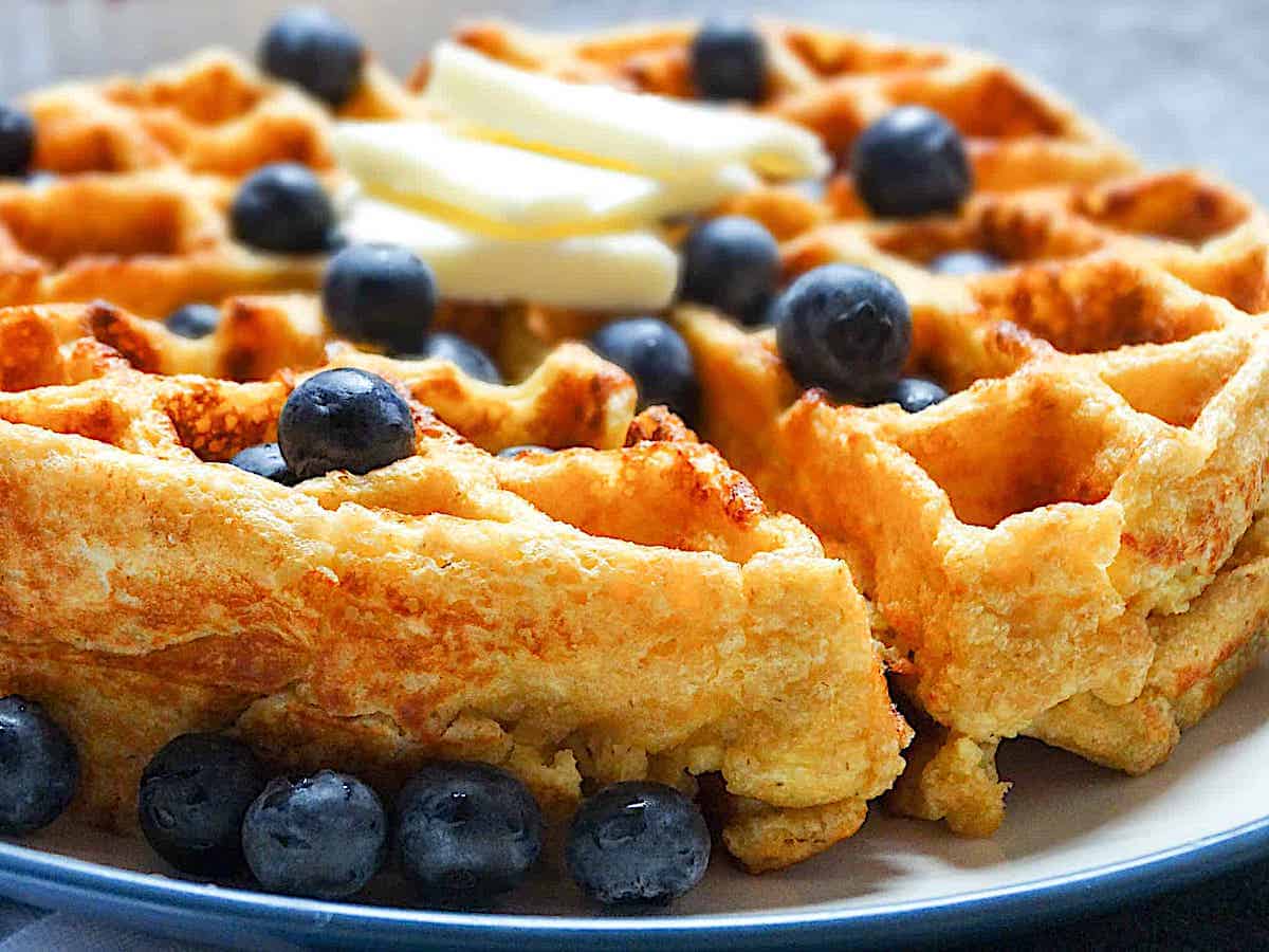 side shot of a cottage cheese waffle topped with blueberries and butter