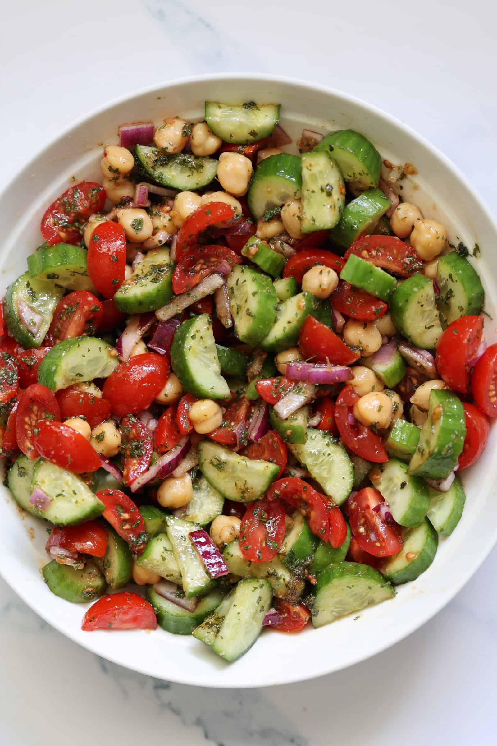 tomato and cucumber tomato salad in a white bowl
