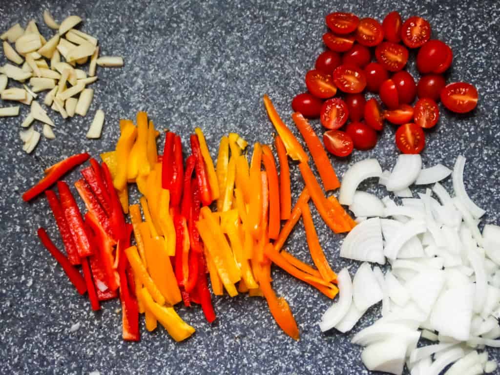 vegetables and garlic chopped on a grey oversized cutting board