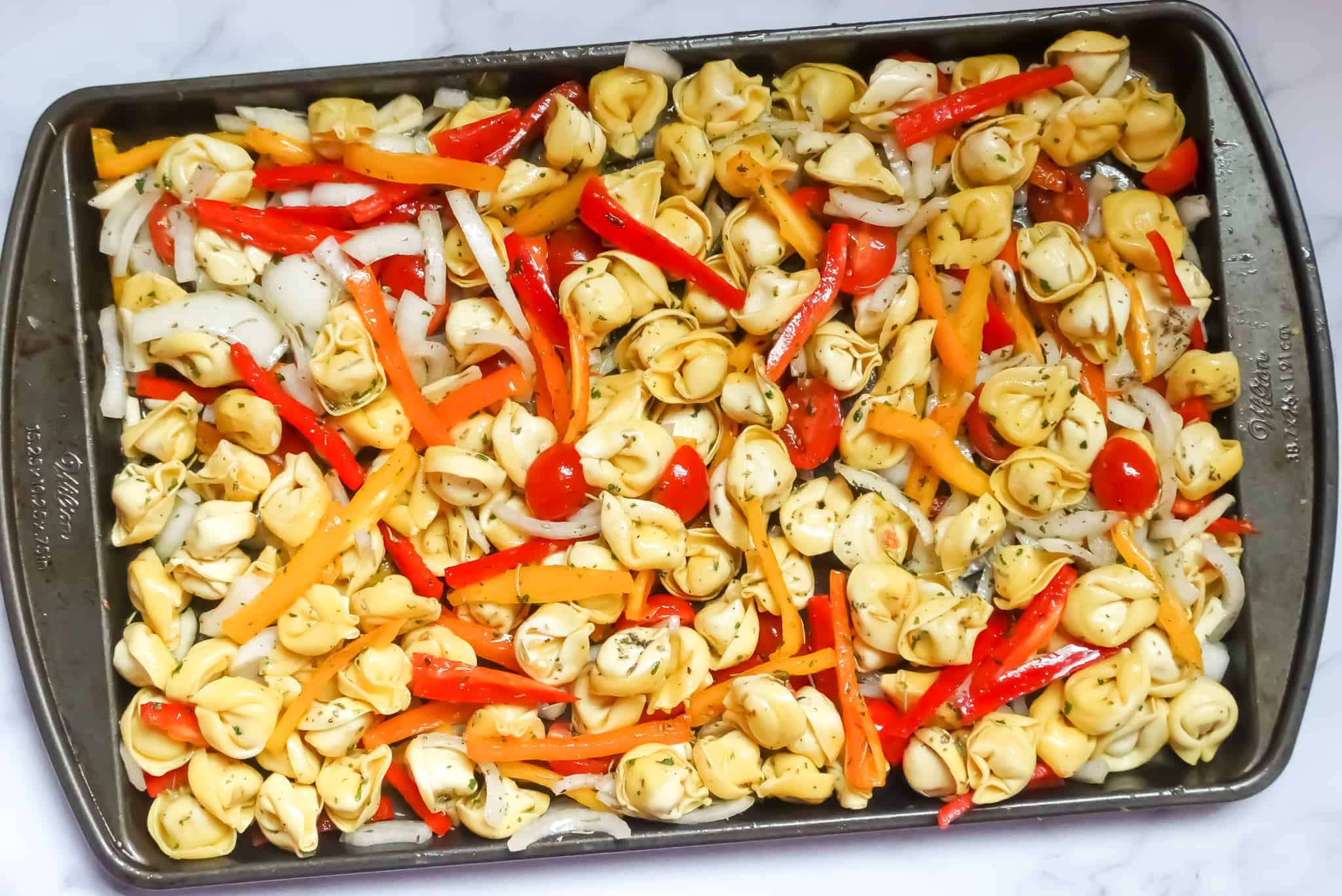 sheet pan tortellini with roasted vegetables on a baking pan