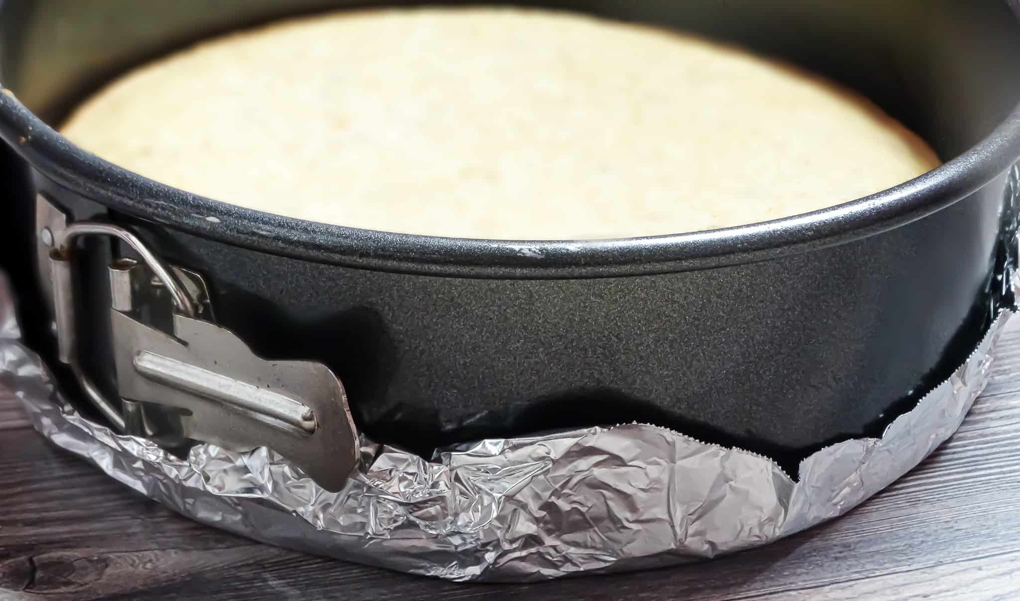 lemon cake batter in a springfoam pan wrapped in foil