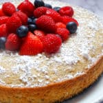 lemon olive cake topped with mixed berries and sprinkled with powdered sugar