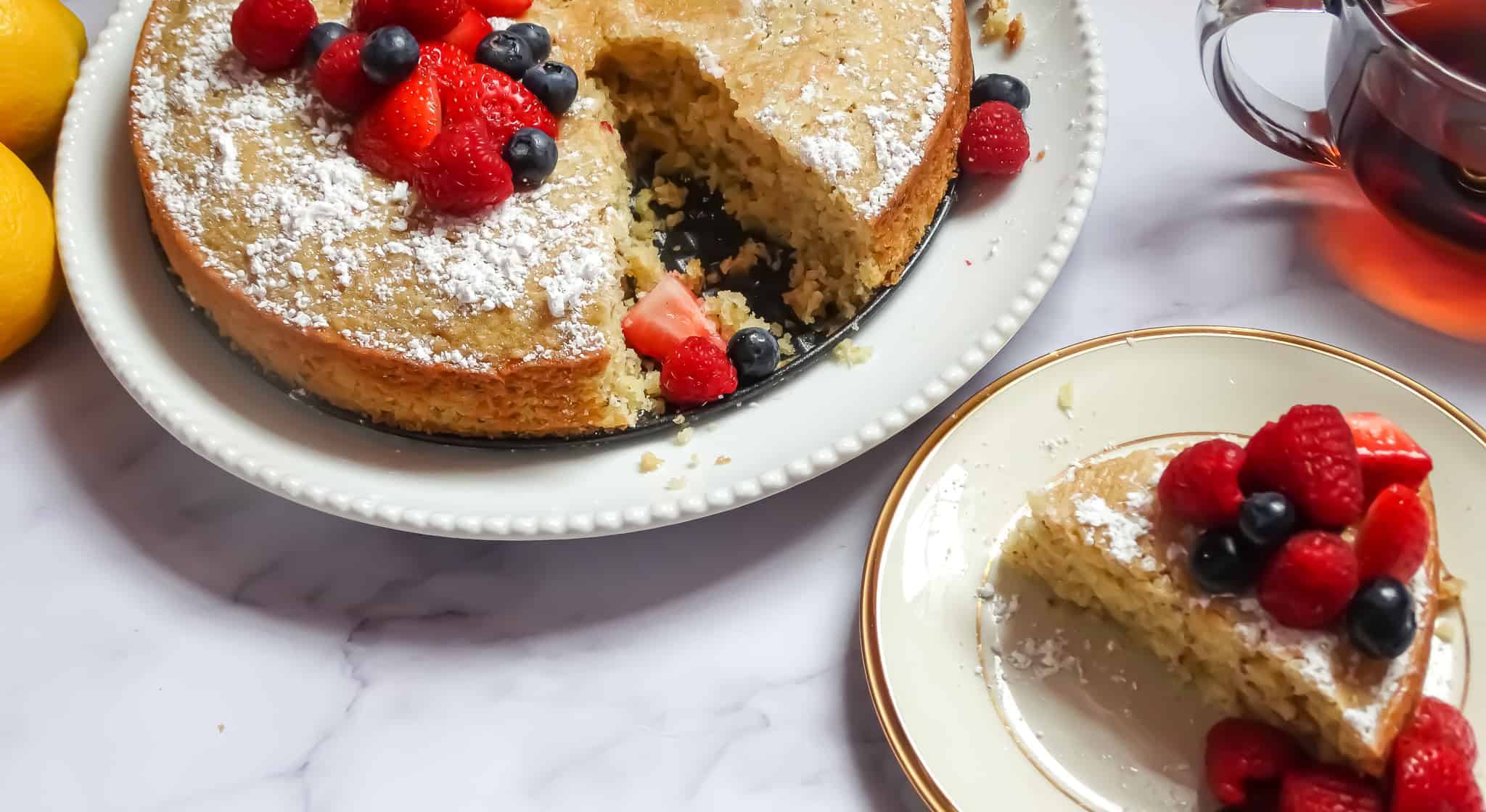 olive oil cake with lemon topped with chopped berries and sprinkled with powdered sugar