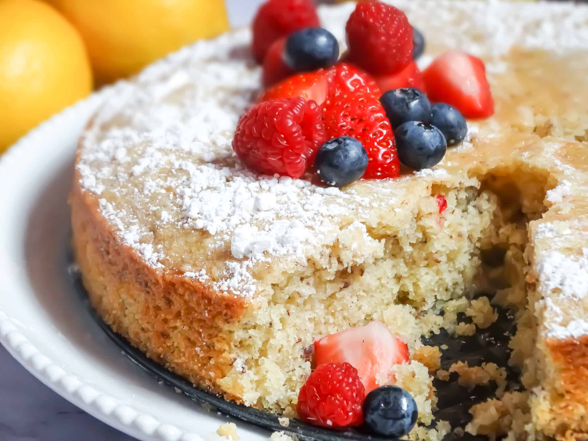 sliced olive oil cake topped with powdered sugar and berries
