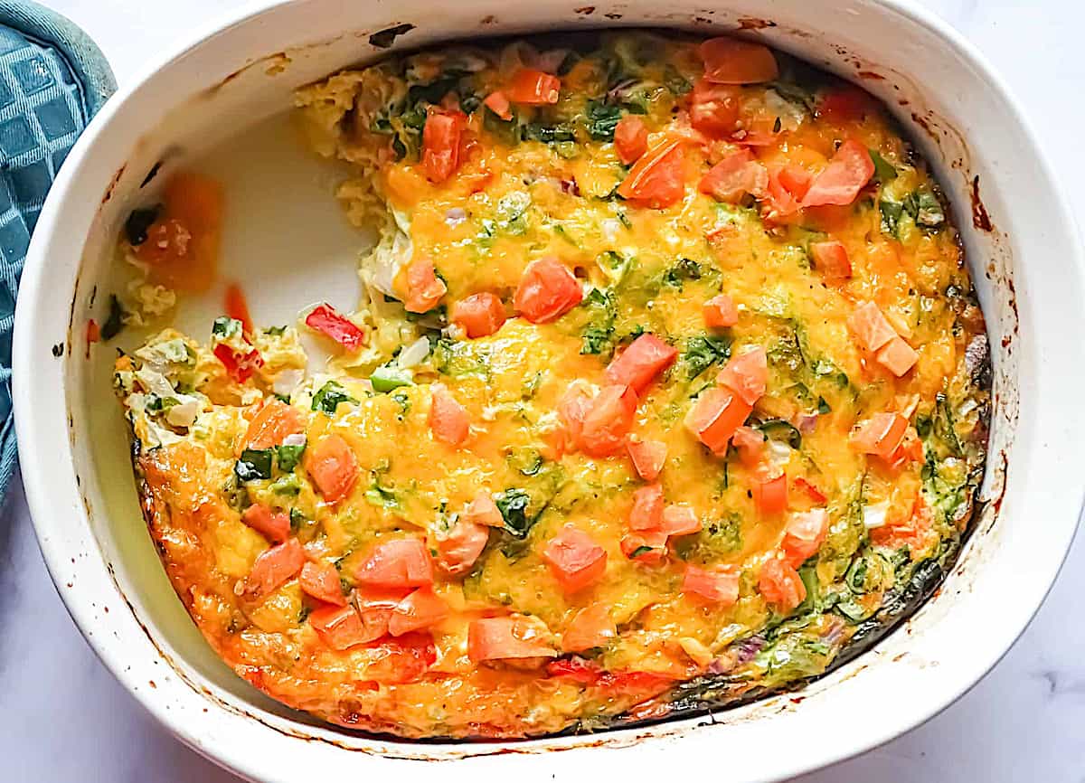 oven baked garden veggie omelette in a casserole pan with 1 slice cut out