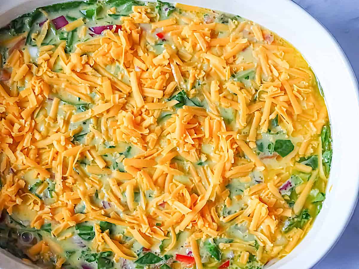 omelette mix topped with cheddar cheese in a casserole pan