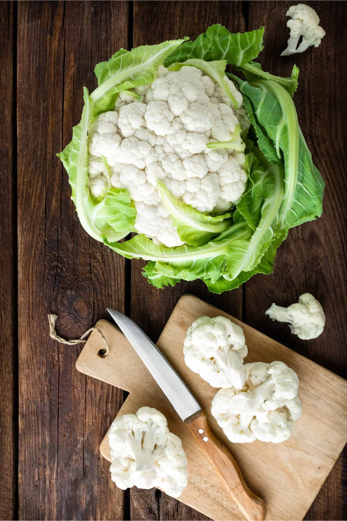 a head of cauliflower being chopped on a cutting board