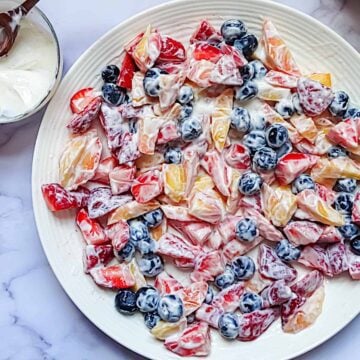 summer berry salad tossed with yogurt on a white plate
