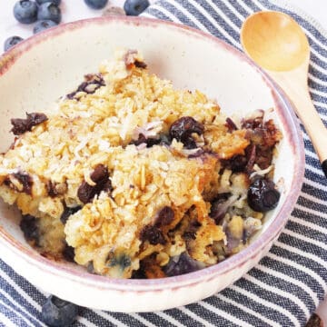 blueberry baked oatmeal in a small dish topped with coconut and sliced almonds