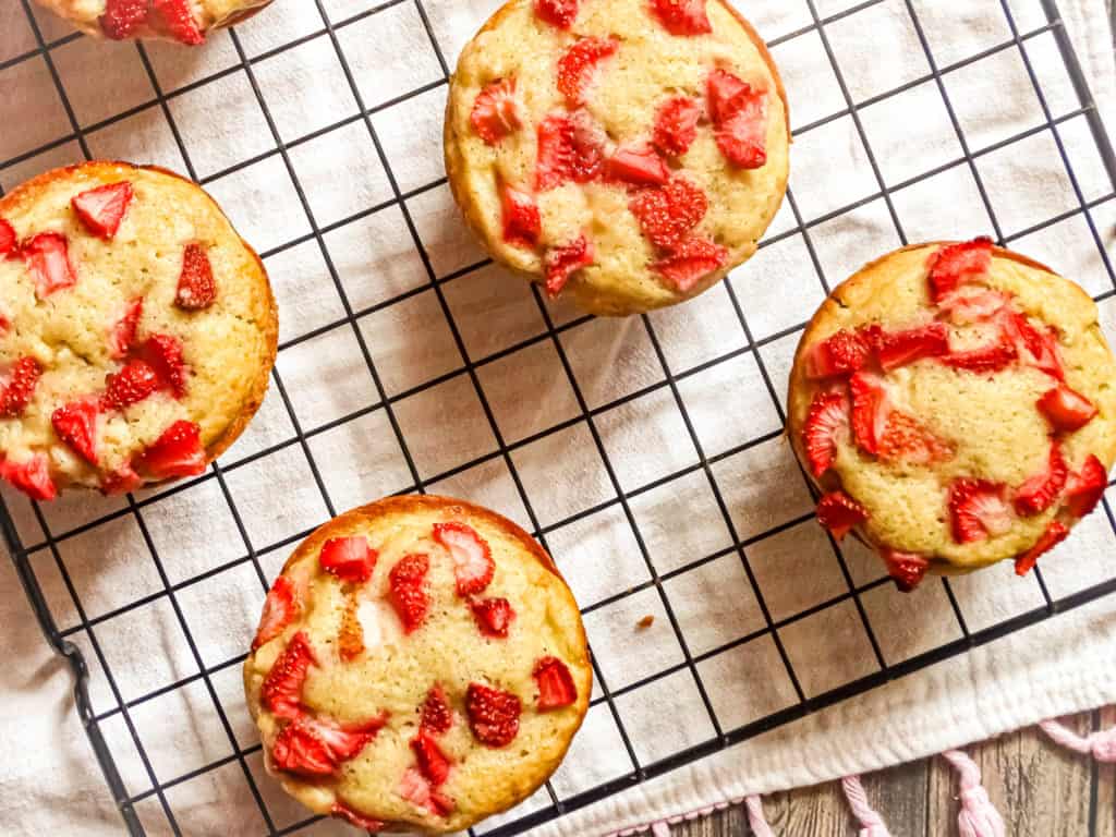 the best banana strawberry muffins on a wire rack topped with strawberries