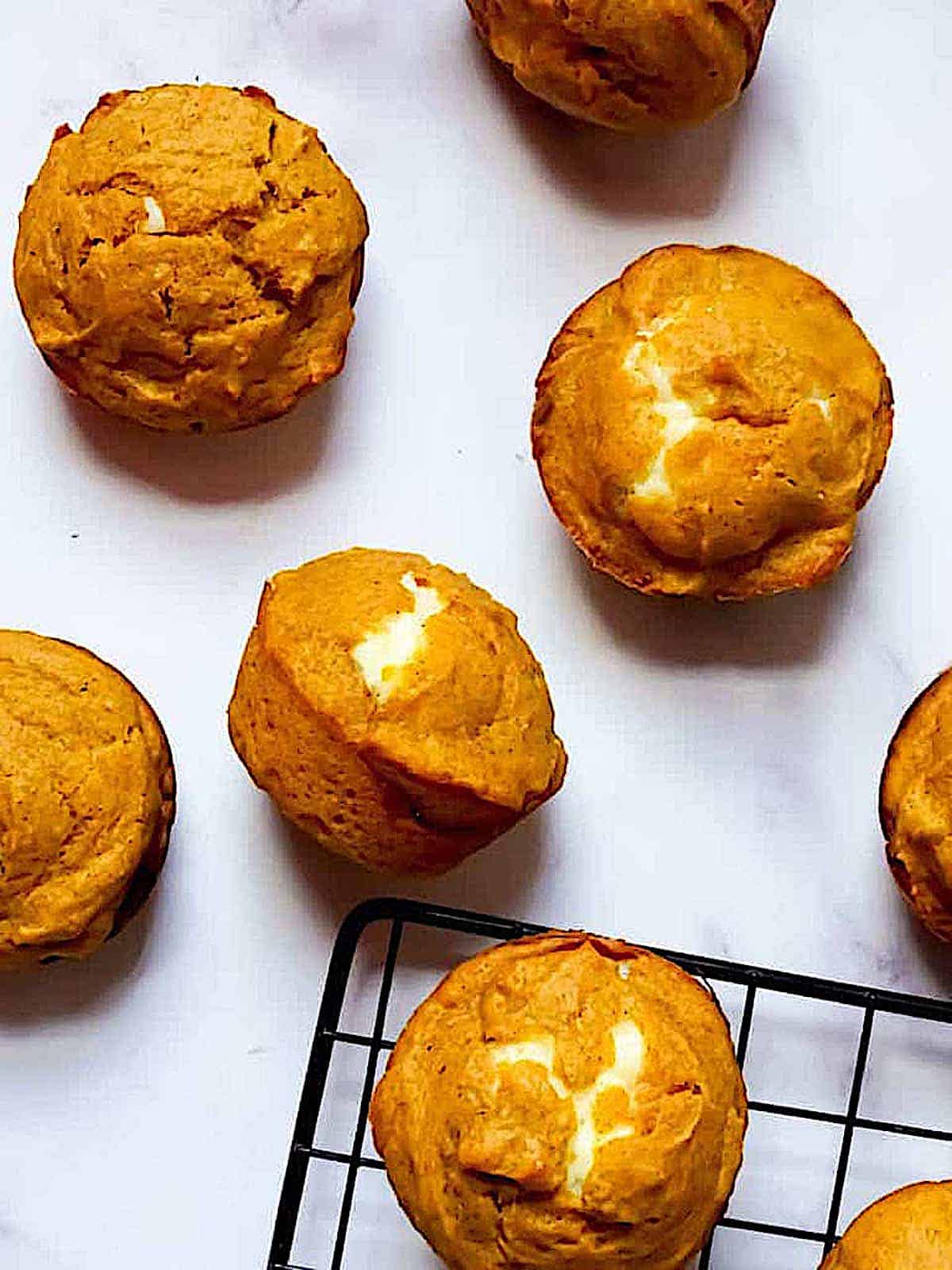 pumpkin muffins with cream cheese filling on a cooling rack