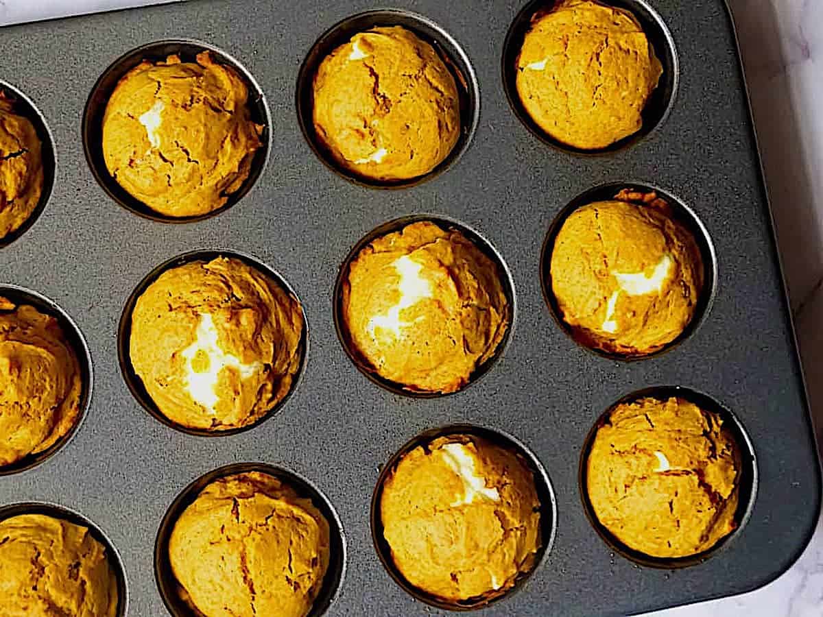 cooked pumpkin cream cheese muffins in a tin